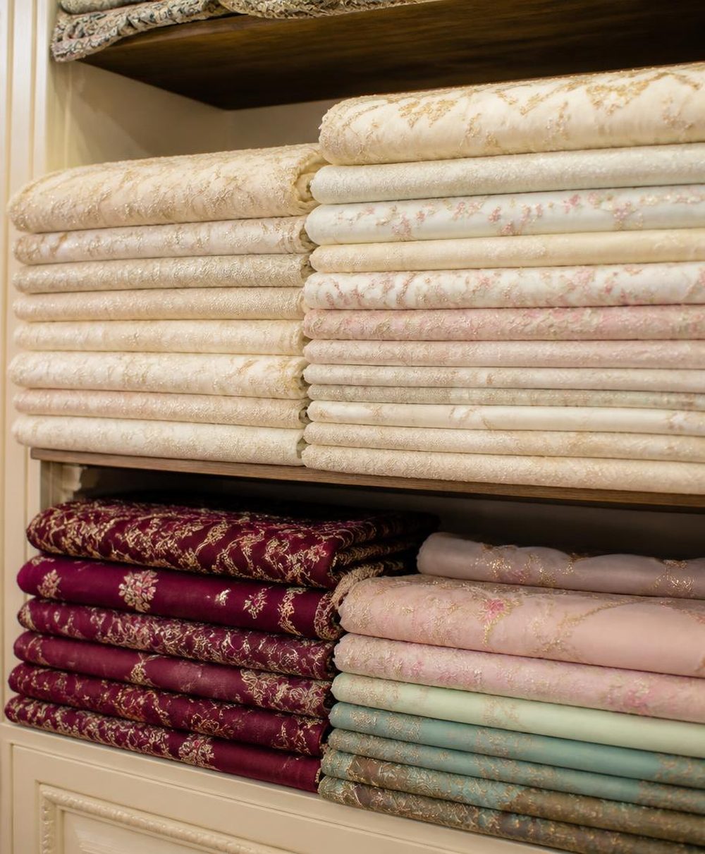 Folded suit fabrics stacked on the shelves of the tailoring shop